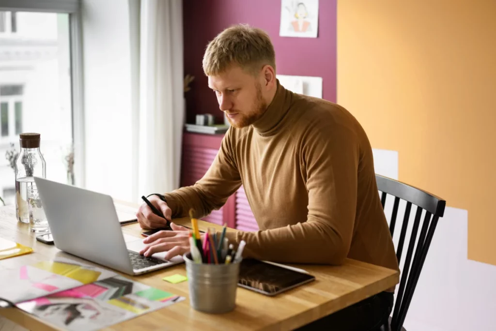 homem adulto ilustrador em frente ao computador mexendo em tablet - criador de site