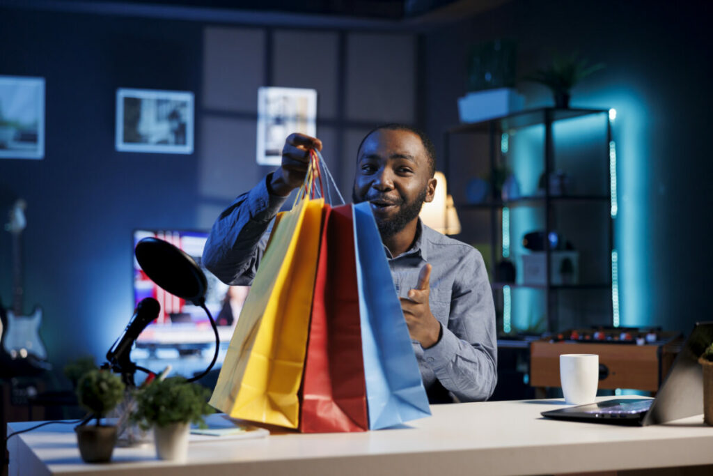 homem influencer mostrando sacolas de compras - digital commerce