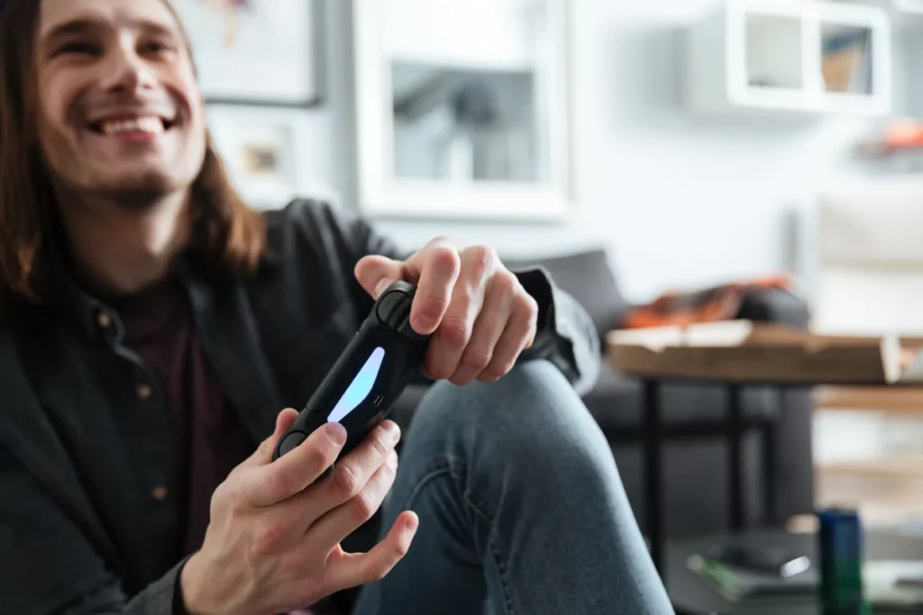 homem sorridente sentado jogando videogame - loja de produtos eletronicos