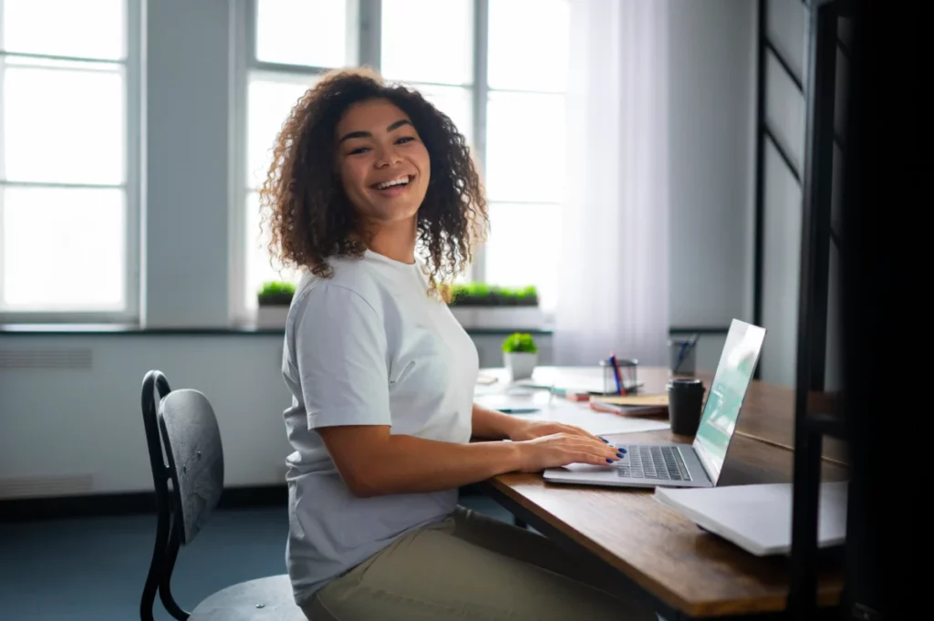 mulher no escritório sorrindo e trabalhando no computador - como fazer uma loja virtual