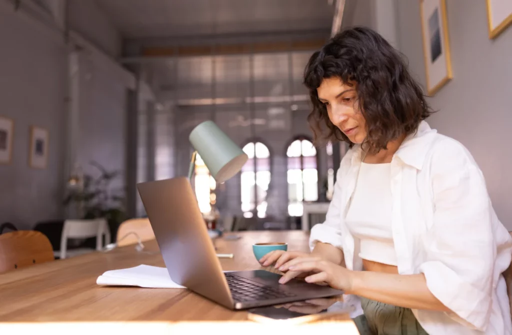 mulher sentada à mesa mexendo no computador como começar a vender na internet