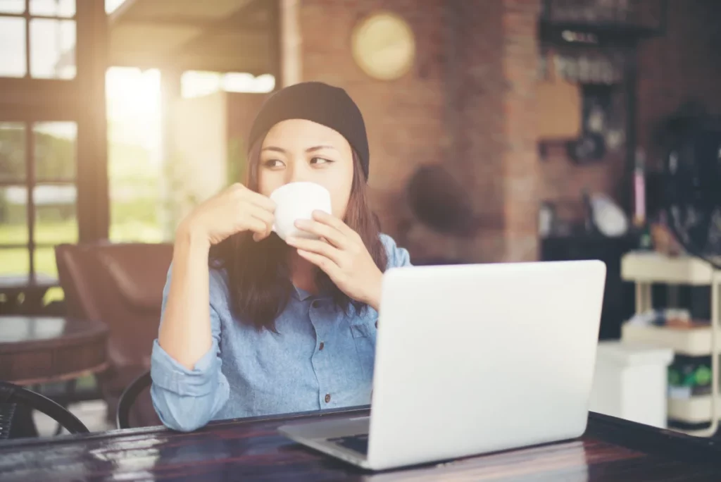 mulher tomando café enquanto trabalha no computador - como fazer uma loja virtual