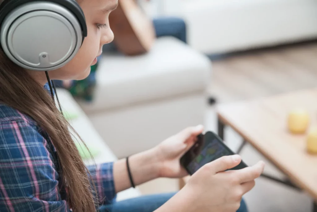 mulher usando fones de ouvido enquanto joga no celular - loja de produtos eletronicos