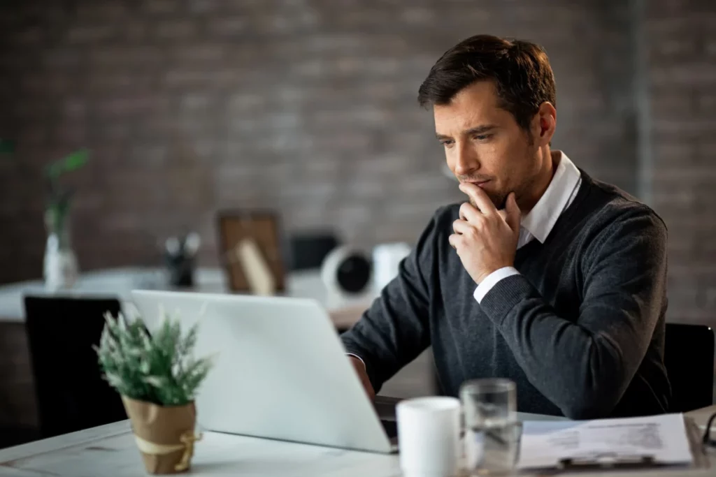 homem de negócios pensativo em frente ao notebook - quero empreender mas não tenho ideias