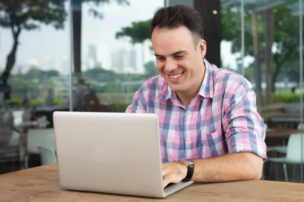 homem feliz mexendo no notebook ao ar livre - o que mais vende na internet