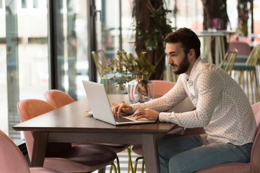 vista lateral de homem  sentado à mesa trabalhando em frente ao computador - o que é newsletter