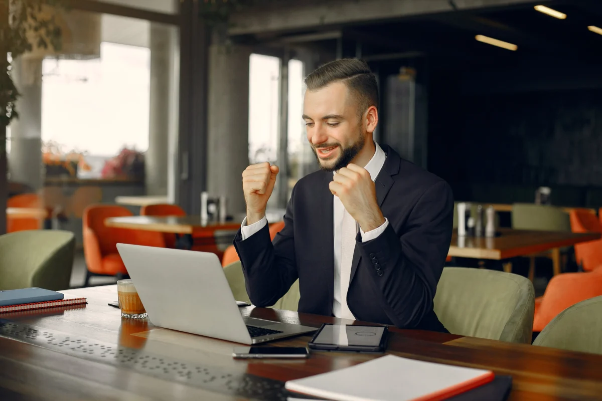 homem de negócios bem vestido comemorando em frente ao notebook - maiores marketplaces brasil