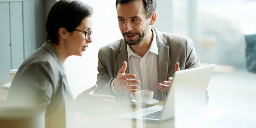 homem-e-mulher-conversando-sentados-atras-de-um-notebook-o-que-e-upsell