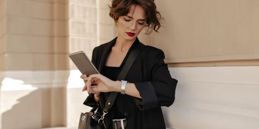 mulher-de-negocios-elegante-com-bolsa-segurando-tablet-enquanto-olha-as-hora-no-relogio-de-pulso-marcas-de-relogios-femininos-mais-vendidos