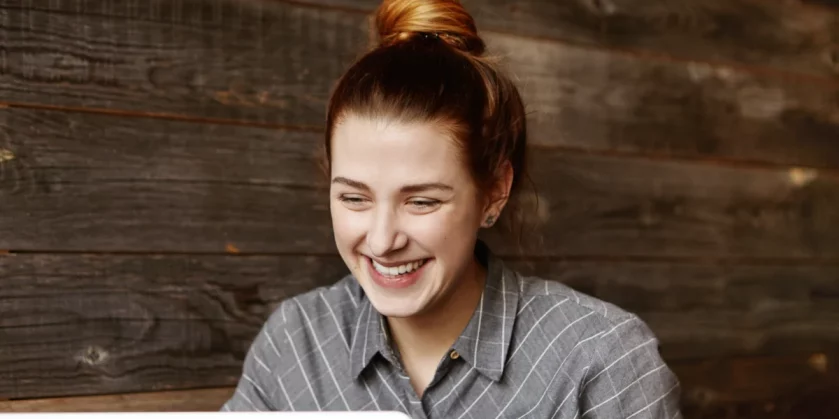 mulher-ruiva-com-o-cabelo-preso-sorrindo-ao-mexer-no-computador-como-vender-com-estrategias-rapidas